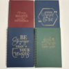 Set of custom spiral journals in assorted colours with engraved motivational sayings on the covers.
