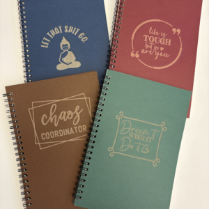 Set of custom spiral journals in assorted colours with engraved motivational sayings on the covers.